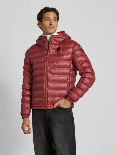 Männermodel trägt Steppjacke mit Zweiwege-Reißverschluss Modell 'CHARLES' von Blauer USA in Rot, Reißverschlusstaschen, Label-Detail, Ganzkörperansicht von vorne. Rückenlänge 67 cm, Schulterbreite 64 cm, Brustweite 53 cm, Ärmellänge 66 cm, Regular Fit.