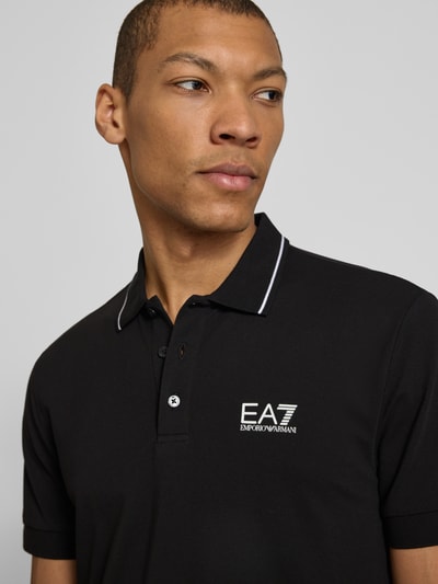 Männermodel trägt Regular Fit Poloshirt mit Logo-Print von EA7 Emporio Armani, Schwarz, Kurzarm, Nahaufnahme Oberkörper