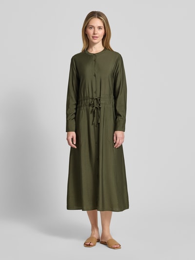 Frauenmodel trägt Relaxed Fit Midikleid aus Viskose-Mix Modell 'Mariela' von Guido Maria Kretschmer in Khaki mit Tunnelzug, Langärmelig, Rundhalsausschnitt, durchgehender Knopfleiste, aufgesetzten Taschen, Ganzkörperansicht von vorne.
