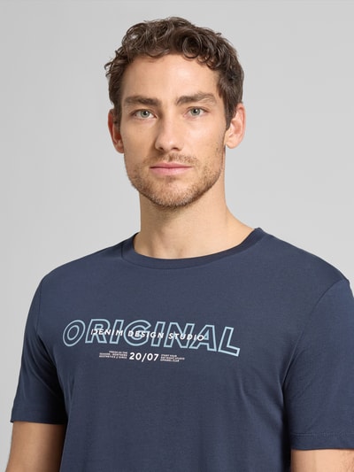 Męski model nosi Regular Fit T-Shirt aus reiner Baumwolle von Tom Tailor Denim, efekt: jednolity kolor, z napisem z logo, okrągły dekolt, krótki rękaw, bawełna, zbliżenie na górną część ciała.