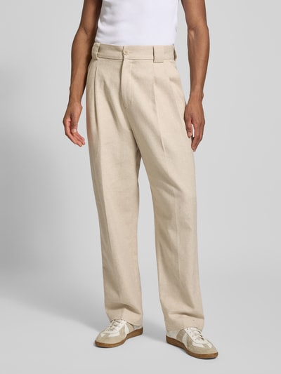 Męski model nosi Relaxed Fit Stoffhose mit Gürtelschlaufen od JAKE*S STUDIO MEN, beżowy, szerokie nogawki, przód, zbliżenie na nogi. Szerokość w rozmiarze M: 45 cm, długość nogawki od wewnątrz: 77 cm, kieszenie z przodu i z tyłu, zakładki, rozporek na guzik i zamek.