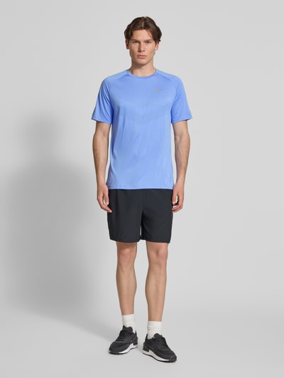 Männermodel trägt Funktionsshirt mit Logo und Rundhalsausschnitt Modell 'Stride' von NIKE TRAINING in Blau, Regular-Fit, Ganzkörperansicht von vorne. Rückenlänge bei Größe M: 73 cm.