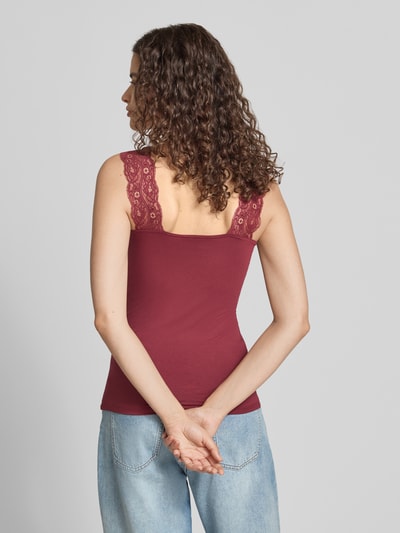 Frauenmodel trägt Slim Fit Tanktop aus Viskose-Mix Modell 'BARBERA' von PIECES in Bordeaux mit Spitzen-Trägern, Ganzkörperansicht Rückansicht.
