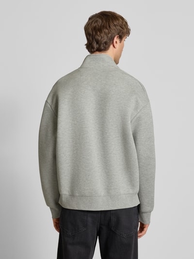 Männermodel trägt Sweatjacke mit Stehkragen von Carhartt Work In Progress in Grau, lockerer Schnitt, Rückenansicht, Ganzkörperansicht Rückansicht.