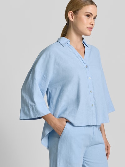 Frauenmodel trägt Boxy Fit Bluse mit V-Ausschnitt Modell 'Lava' von FREE/QUENT aus Leinen-Viskose-Mix in Hellblau, lockere Form, Hemdblusenkragen, Knopfleiste, 3/4-Arm, feine Stoffstruktur, Ganzkörperansicht von vorne.