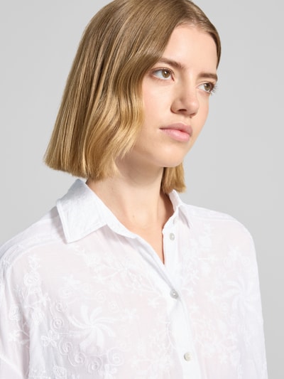 Frauenmodel trägt Regular Fit Hemdbluse mit floralem Allover-Stitching von Christian Berg Woman in Weiß, Reine Baumwolle, Hemdblusenkragen, Langärmelig, durchgängige Knopfleiste, Nahaufnahme Oberkörper.