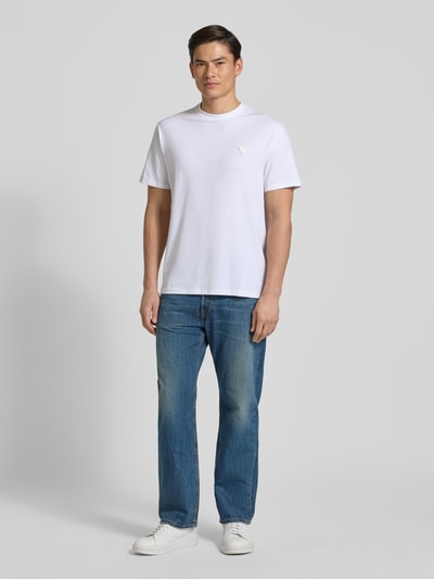 Männermodel trägt T-Shirt mit Logo und Rundhalsausschnitt von Guess, Baumwoll-Mix mit Modal-Anteil, Relaxed-Fit, Rückansicht Ganzkörperansicht von vorne.