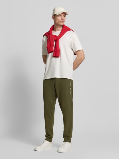 Mannelijk model draagt Comfort Fit Sweatpants aus Baumwoll-Mix van Tommy Hilfiger in effen olijfgroen, sweatmateriaal met label stitching, geribbelde taille en boorden, zijzakken, tunnelkoordsluiting, ganzlichaamsaanzicht van voren.