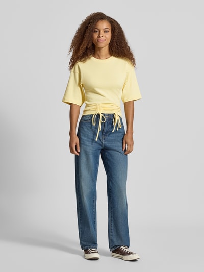 Kobiece modelka nosi damski t-shirt z bawełny, prosty krój, model 'MALLE' od Topshop, okrągły dekolt, marszczenia z wiązaniem, opuszczone ramiona, długość tyłu w rozmiarze S: 66 cm, widok całej sylwetki z przodu