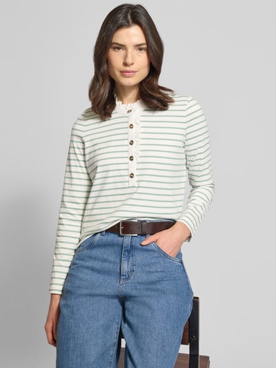 Frauenmodel trägt Longsleeve mit Knopfleiste und Rüschen von Christian Berg Woman aus reiner Baumwolle im Regular-Fit mit Stehkragen, Hell mit grünen Streifen, Obermaterial fein, Rückenlänge bei Größe S 59 cm, Nahaufnahme Oberkörper.