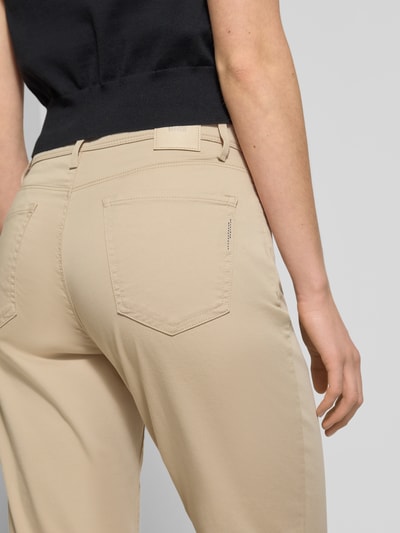 Vrouwenmodel draagt Flared Fit Stoffhose met Lyocell-Anteil Modell 'Carola' van Brax in beige, 5-pocket-design, elastische katoenmix, detailopname van achteren.