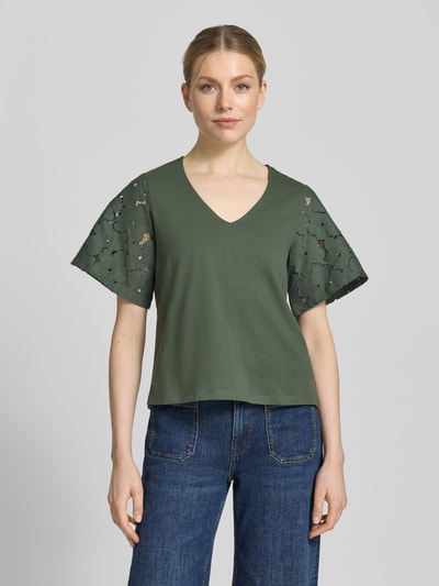 Vrouwenmodel draagt Regular Fit Blusenshirt uit puur katoen model 'VILLA' van Vero Moda, look: effen, met kant, V-hals, korte mouw, jersey, dames, kleuren: donkergroen, textuur: gladde stof en kanten details, pasvorm: regular fit, materiaal: puur katoen, model: vooraanzicht van het hele lichaam.