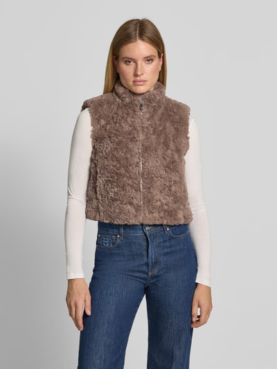 Frauenmodel trägt Regular Fit Weste aus Kunstfell mit Stehkragen von monari in Braun, weiche Textur, kombiniert mit Jeans, Nahaufnahme Oberkörper. Damen Weste von monari, Kunstfell, Regular Fit, Stehkragen, Reißverschluss, Rückenlänge 47 cm, Schulterbreite 39 cm, Brustweite 45 cm.