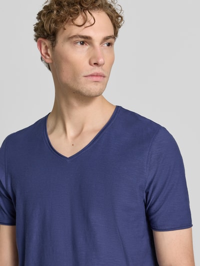 Mannenmodel draagt T-shirt met V-hals en rolzoom van MCNEAL in blauw, puur katoen, regular fit, ruglengte maat M 81 cm, nahaufnahme bovenlichaam.