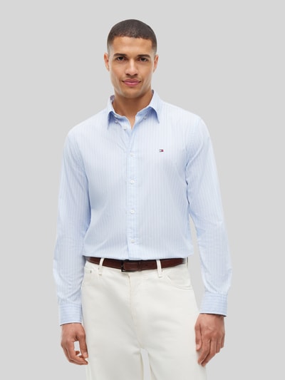 Männermodel trägt Body Fit Freizeithemd aus reiner Baumwolle von Tommy Hilfiger in Hellblau mit feinen Streifen, Ganzkörperansicht von vorne.