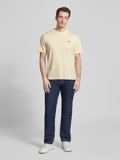 Męski model nosi Regular Fit Poloshirt aus reiner Baumwolle od Lacoste, efekt: jednolity kolor, krój regular fit, wyhaftowane logo, okrągły dekolt, krótki rękaw, materiał: bawełna, Ganzkörperansicht von vorne.