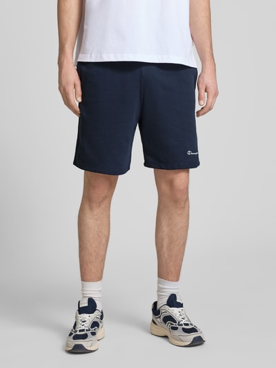 Mannenmodel draagt Shorts met elastische tailleband en label-stitching van CHAMPION, katoenmix, regular fit, donkerblauw, vooraanzicht heup tot knie.