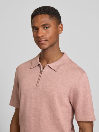 Männermodel trägt Regular Fit Poloshirt mit Reißverschluss Modell 'MILANO' von Jack & Jones Premium in Rosa, Nahaufnahme Oberkörper. Bio-Baumwoll-Mix, Label-Detail.