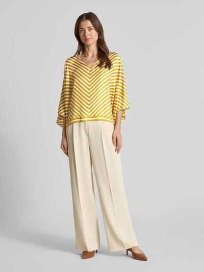 Frauenmodel trägt Bluse aus Seide mit V-Ausschnitt von Windsor in Gelb-Weiß, Loose-Fit, Fledermausärmel, Rückenlänge 55 cm, Ganzkörperansicht von vorne.