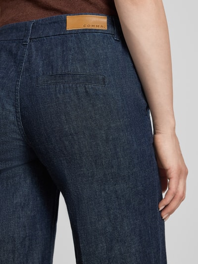 Frauenmodel trägt Jeans mit Bügelfalten und Eingrifftaschen von comma, dunkelblau, reine Baumwolle, Detailaufnahme Rückansicht.