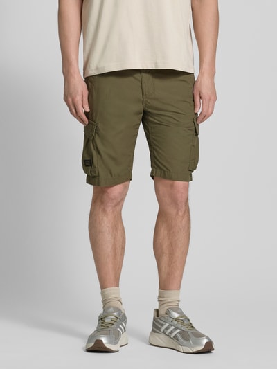Mannelijk model draagt Bermudas met Cargotaschen van camel active in olijfgroen, puur katoen, regular fit, steekzakken, cargozakken, labeldetail, bandwijdte maat 32: 44 cm, binnenbeenlengte maat 32: 26 cm. Ganzkörperansicht van voren.