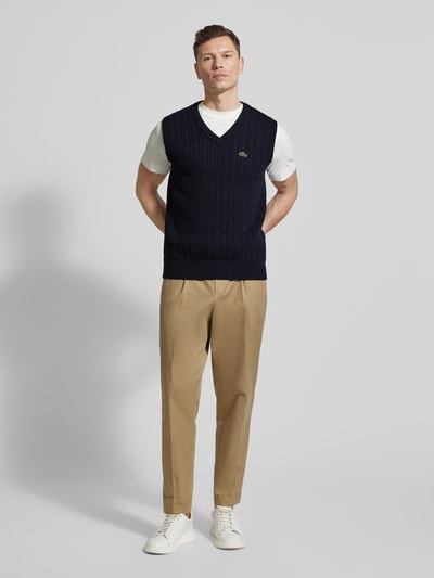Mężczyzna nosi Regular Fit Pullunder aus Baumwoll-Mix od Lacoste, granatowy, wzór warkoczowy, prążkowany dół, detal z logo, widok całej sylwetki z przodu