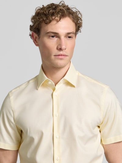 Männermodel trägt Regular Fit Business-Hemd mit Kentkragen von Christian Berg Men in zartem Gelb aus Reine Baumwolle, Knopfleiste, Kurzärmelig, Nahaufnahme Oberkörper. Rückenlänge 81 cm, Schulterbreite 49 cm, Ärmellänge 24 cm bei Größe 39/40.