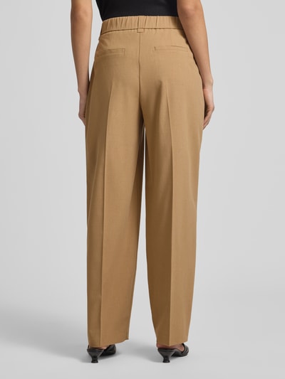 Frauenmodel trägt Barrel Fit Hose Modell 'Moira Bloom' von OPUS PANTS in Beige mit Bügelfalten, aus Baumwoll-Mix, Ganzkörperansicht Rückansicht.
