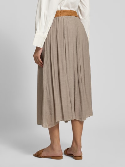 Frauenmodel trägt beigefarbenen Midirock aus Viskose-Mix mit Gürtel von Apricot, leichte Faltenstruktur, A-Linie, Ganzkörperansicht Rückansicht. Bundweite 35 cm, Gesamtlänge 84 cm.