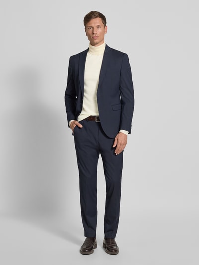 Männermodel trägt Rollkragenpullover mit gerippten Abschlüssen von Emporio Armani in Beige, kombiniert mit dunkelblauem Anzug, Schurwoll-Mix mit Stretch-Anteil, Slim Fit, Ganzkörperansicht von vorne.