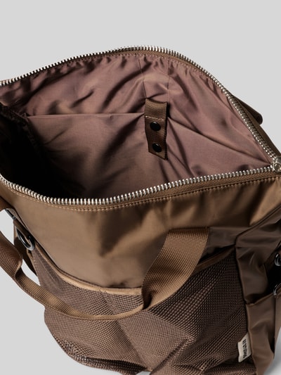 Produktfoto, Rucksack mit Logo-Detail von AY STUDIOS in Braun mit Netz-Taschen, Reißverschluss, geräumigem Hauptfach, Detailaufnahme, Kontext: Herren Rucksack, verstellbare Schulterriemen, Maße 42x54x13 cm, Schulterriemenlänge 98 cm.
