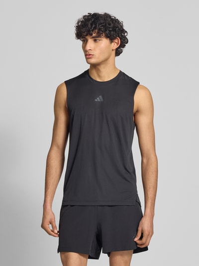 Männermodel trägt Regular Fit Sport Tank Top mit Label Print von adidas Training in Schwarz, unifarben, feines Strukturmuster, Ganzkörperansicht von vorne.