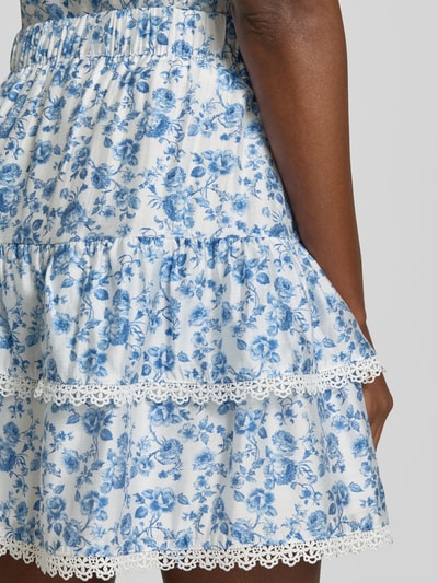 Frauenmodel trägt Ausgestellter Rock aus Viskose-Mix Modell 'BLISS' von Vero Moda, Optik:Allover-Muster floral, Mini-Länge, Bundabschluss: Elastisch, Materialverarbeitung: Popeline, Detailaufnahme.