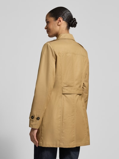 Frauenmodel trägt Trenchcoat mit Ärmelriegeln von Fuchs Schmitt, beigefarbener Stoff, Knopfleiste, Rückenriegel, Ganzkörperansicht Rückansicht.
