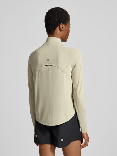Frauenmodel trägt Longsleeve mit Troyer-Kragen Modell 'NAGINO' von ASICS TIGER in hellem Beige, reflektierender Logo-Print, Rückansicht.