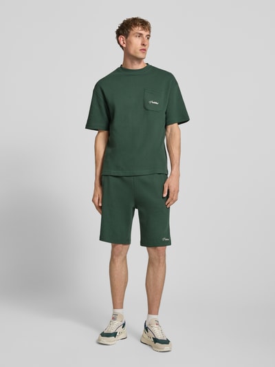 Männermodel trägt T-Shirt mit Strukturmuster und Label-Stitching von PROHIBITED in Dunkelgrün, Reine Baumwolle, Regular-Fit, Brusttasche, Ganzkörperansicht von vorne.