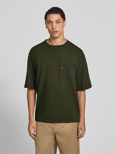 Męski model nosi Loose Fit T-Shirt aus reiner Baumwolle von Levi's®, oliwkowa zieleń, prosty krój, bawełniana faktura, kieszonka, Ganzkörperansicht von vorne