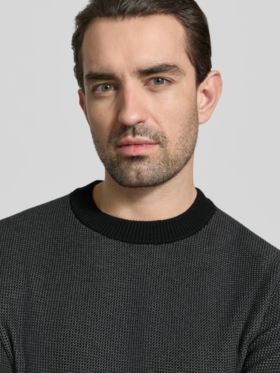 Männermodel trägt Regular Fit Strickpullover aus Baumwoll-Schurwoll-Mix Modell 'HESTRO' von BOSS, Allover-Muster, Nahaufnahme Oberkörper.