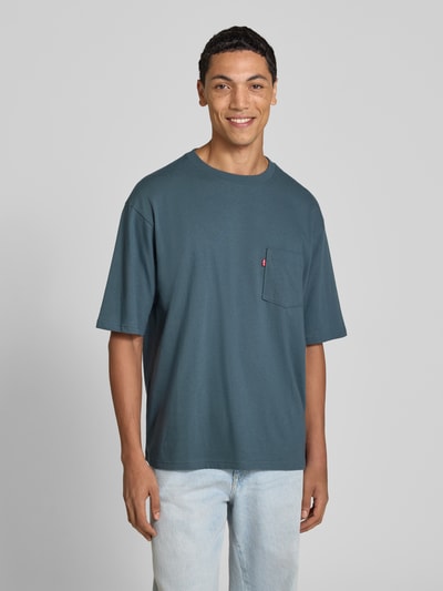 Männermodel trägt Regular Fit T-Shirt aus reiner Baumwolle von Levi's® in Blau, schlichte Struktur, kombiniert mit heller Jeans, Ganzkörperansicht von vorne.