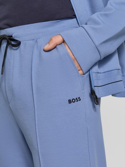 Männermodel trägt Regular Fit Sweatpants aus Baumwoll-Mix Modell 'JT_Member Hurley' von BOSS Green in Hellblau, Nahaufnahme Oberkörper. Unifarbene Sweat-Pants mit Tunnelzug, seitlichen Taschen, Label Stitching, fixierten Bügelfalten und elastischem Bund.
