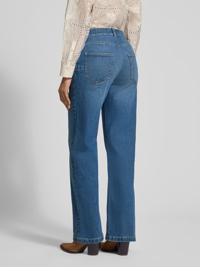 Frauenmodel trägt Flared Jeans mit Eingrifftaschen von Jake*s Collection in Blau mit Used-Look und Gesäßtaschen, Ganzkörperansicht Rückansicht.