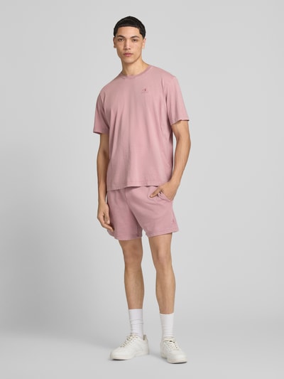 Männermodel trägt Sweatshorts mit Eingrifftaschen von CHAMPION in Rosa, Baumwoll-Mix, Regular Fit, Nahaufnahme Ganzkörperansicht von vorne.