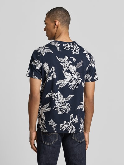 Männermodel trägt T-Shirt mit Rundhalsausschnitt und Label-Detail von Lerros, dunkelblau mit weißem Blumenmuster, gerade geschnitten, Rückenlänge 70 cm, Ganzkörperansicht Rückansicht.