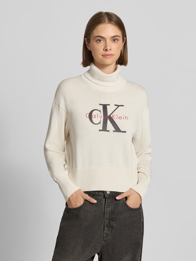 Frauenmodel trägt Regular Fit Pullover aus reiner Baumwolle von Calvin Klein Jeans in Creme mit Logo, strukturierte Oberfläche, Nahaufnahme Oberkörper.