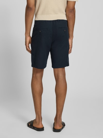 Männermodel trägt Regular Fit Chinoshorts aus Baumwoll-Leinen-Mix Modell 'BRODY' von SELECTED HOMME in Dunkelblau, Flammgarnstruktur, unifarben, mit Taschen und Knopfverschluss, Ganzkörperansicht Rückansicht.