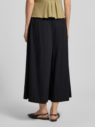 Frauenmodel trägt Wide Fit Stoffhose mit elastischem Bund Modell 'Sunna' von My Essential Wardrobe in Schwarz mit Falten-Optik, Bundweite bei Größe 36: 36 cm, Innenbeinlänge: 58 cm, Ganzkörperansicht Rückansicht.