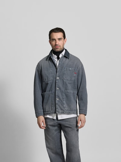 Männermodel trägt Regular Fit Hemdjacke in Denim-Optik von Diesel aus reiner Baumwolle, mit aufgesetzten Taschen und Knopfleiste, Ganzkörperansicht von vorne.