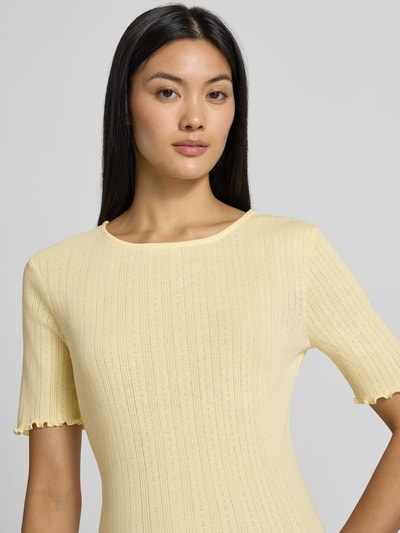 Frauenmodel trägt T-Shirt mit Wellensaum und Rundhalsausschnitt Modell 'UNICA' von b.young in Gelb, Ripp-Optik, Slim Fit, Nahaufnahme Oberkörper.