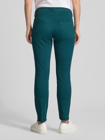 Frauenmodel trägt Tapered Chino aus Baumwoll-Mix von Tom Tailor in Unifarbe Türkis, Relaxed Tapered Passform, Ganzkörperansicht Rückansicht.