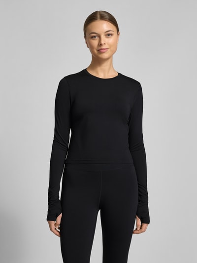 Frauenmodel trägt Slim Fit Longsleeve mit Rundhalsausschnitt Modell 'Feather' von Fabletics, elastischer Material-Mix, schwarz, Ganzkörperansicht von vorne.